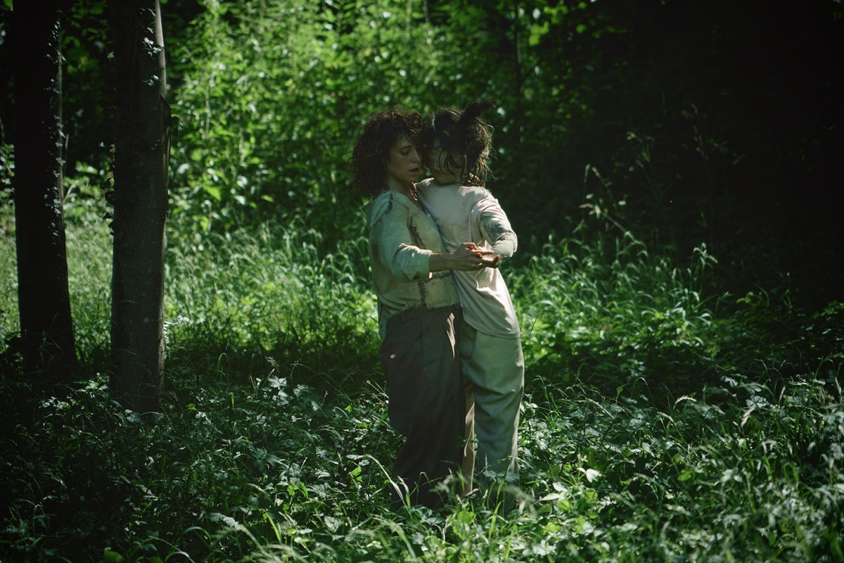 Photo de Maë Rebuttini dansant la valse avec une marionnette dans une forêt 