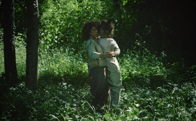 Photo de Maë Rebuttini dansant la valse avec une marionnette dans une forêt 