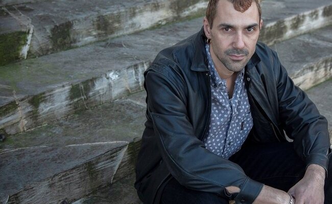 Portrait de Jérémie Nicolas, assis sur des marches 